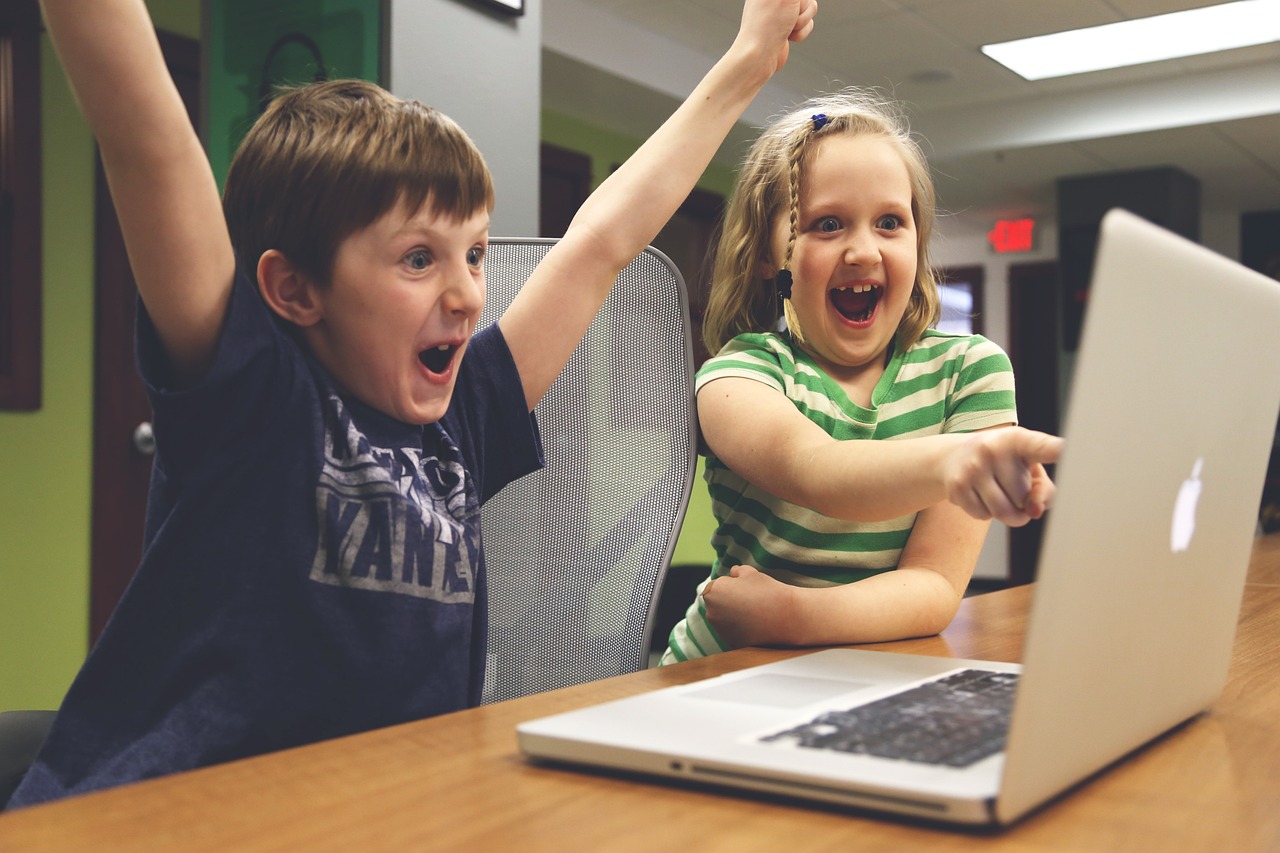 two kids delighted by what they se on a laptop screen